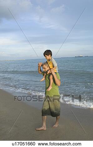 Mid adult man carrying his son on his shoulders View Large Photo Image Stock Image - Mid adult man carrying his son on his shoulders. Fotosearch