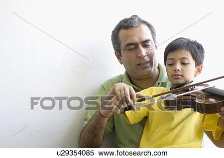 Mid adult man teaching his son how to play a violin View Large Photo Image Stock Photography - Mid adult man teaching his son how to play a violin. Fotosearch