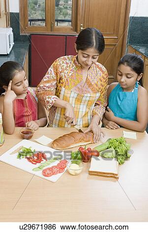 Stock Photograph - Mid adult woman making sandwich with her daughters. Fotosearch