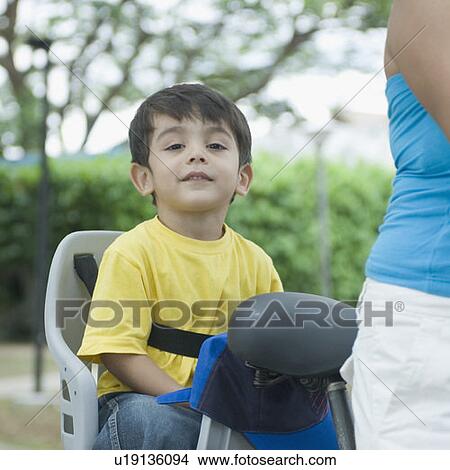 Mid section view of a mid adult woman riding a bicycle and her son sitting behind her View Large Photo Image Picture - Mid section view of a mid adult woman riding a bicycle and her son sitting behind her . Fotosearch