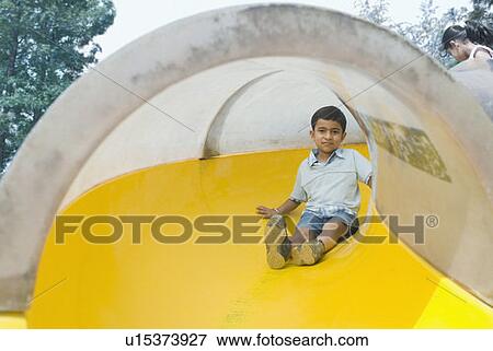 Stock Photo - Portrait of a boy sliding on a slide. Fotosearch