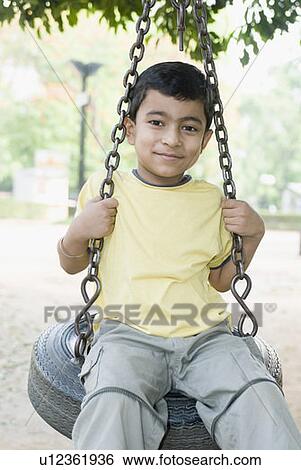 Portrait of a boy swinging on a tire swing View Large Photo Image Stock Photograph - Portrait of a boy swinging on a tire swing. Fotosearch