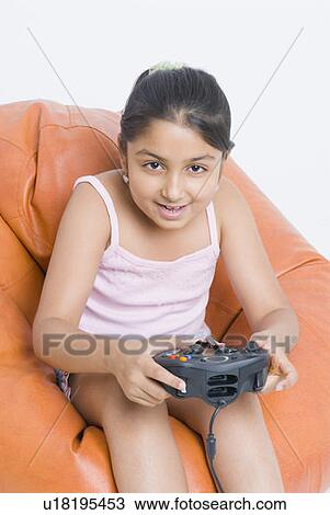 Portrait of a girl sitting on a bean bag and playing a video game View Large Photo Image Stock Image - Portrait of a girl sitting on a bean bag and playing a video game. Fotosearch