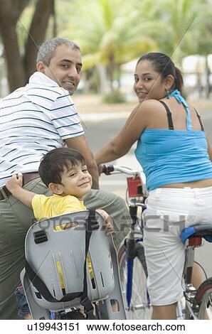 Portrait of a mid adult couple sitting on bicycles with their son View Large Photo Image Stock Image - Portrait of a mid adult couple sitting on bicycles with their son . Fotosearch