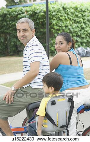 Portrait of a mid adult couple sitting on bicycles with their son View Large Photo Image Stock Photo - Portrait of a mid adult couple sitting on bicycles with their son . Fotosearch
