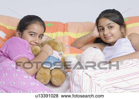 Portrait of two girls lying on the bed View Large Photo Image Stock Photo - Portrait of two girls lying on the bed. Fotosearch