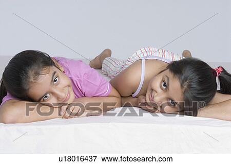 Portrait of two girls lying together on the bed and smiling View Large Photo Image Stock Photo - Portrait of two girls lying together on the bed and smiling. Fotosearch