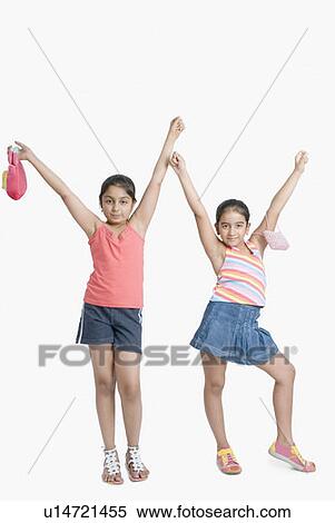 Stock Photography - Portrait of two girls posing with arms raised. Fotosearch