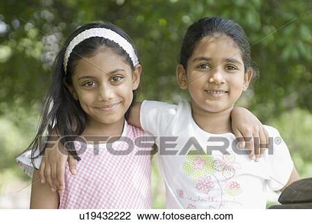 Portrait of two girls standing with their arms around each other View Large Photo Image Stock Image - Portrait of two girls standing with their arms around each other. Fotosearch
