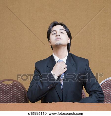 Portrait of a businessman adjusting his tie View Large Photo Image Stock Image - Portrait of a businessman adjusting his tie. Fotosearch
