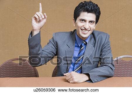 Stock Photograph - Portrait of a businessman raising his hand and smiling. Fotosearch