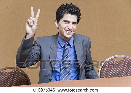 Portrait of a businessman showing a peace sign and smiling View Large Photo Image Stock Photograph - Portrait of a businessman showing a peace sign and smiling. Fotosearch