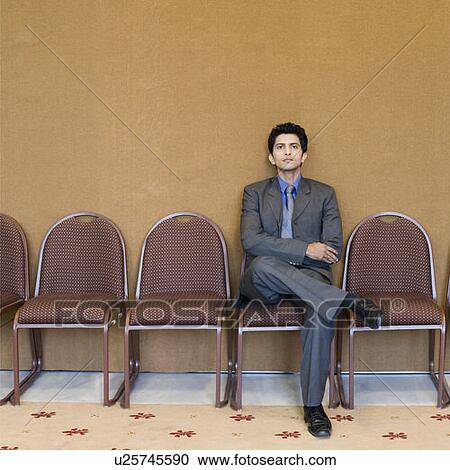 Stock Image - Portrait of a businessman sitting on a chair in a conference room. Fotosearch