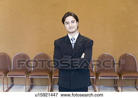 Stock Photo - Portrait of a businessman standing with his arms crossed and smiling. Fotosearch