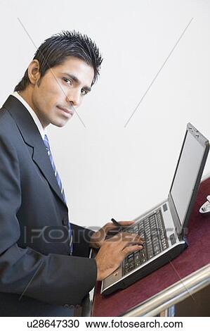 Side profile of a businessman using a laptop at a lectern View Large Photo Image Stock Image - Side profile of a businessman using a laptop at a lectern. Fotosearch