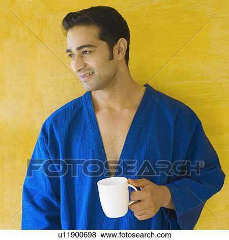 Close-up of a young man holding a cup of coffee and smiling View Large Photo Image Stock Photo - Close-up of a young man holding a cup of coffee and smiling. Fotosearch