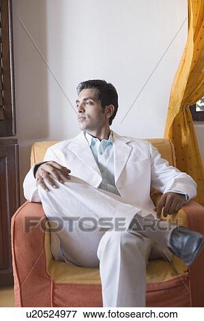 Close-up of a young man sitting in an armchair View Large Photo Image Stock Photo - Close-up of a young man sitting in an armchair. Fotosearch