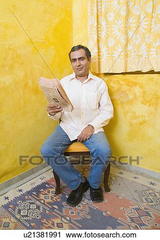 Stock Image - Portrait of a mid adult man reading a newspaper. Fotosearch