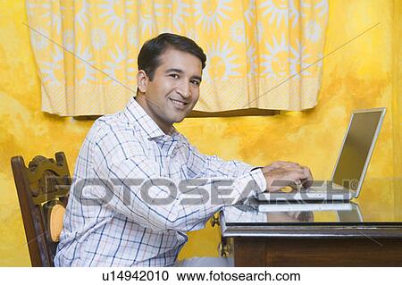 Stock Image - Portrait of a mid adult man using a laptop. Fotosearch