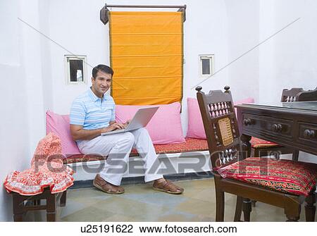 Stock Image - Portrait of a mid adult man using a laptop. Fotosearch