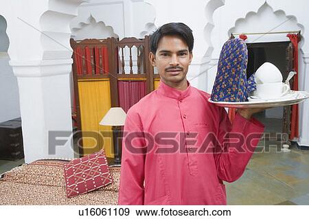Portrait of a waiter carrying a teapot in a tray View Large Photo Image Stock Photo - Portrait of a waiter carrying a teapot in a tray. Fotosearch