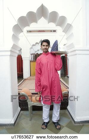 Stock Photo - Portrait of a young man carrying a tea tray. Fotosearch
