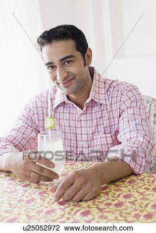 Stock Image - Portrait of a young man holding a glass of lemon juice and smiling. Fotosearch