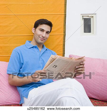 Portrait of a young man holding a newspaper and smirking View Large Photo Image Stock Image - Portrait of a young man holding a newspaper and smirking. Fotosearch