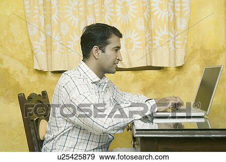 Side profile of a mid adult man using a laptop View Large Photo Image Stock Photo - Side profile of a mid adult man using a laptop. Fotosearch