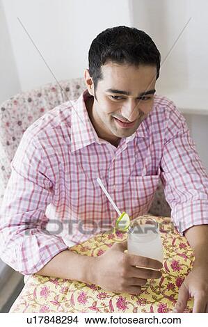 Picture - Young man holding a glass of lemon juice and smiling. Fotosearch