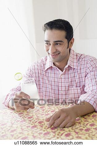 Young man holding a glass of lemon juice and smiling View Large Photo Image Stock Photography - Young man holding a glass of lemon juice and smiling. Fotosearch