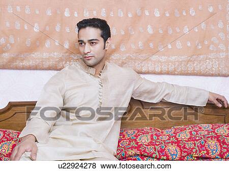 Stock Photo - Young man sitting on the bed. Fotosearch