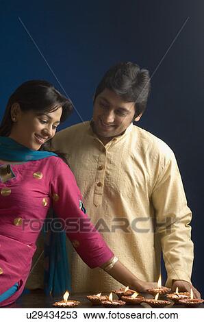 Stock Image - Close-up of a couple arranging oil lamps and smiling. Fotosearch