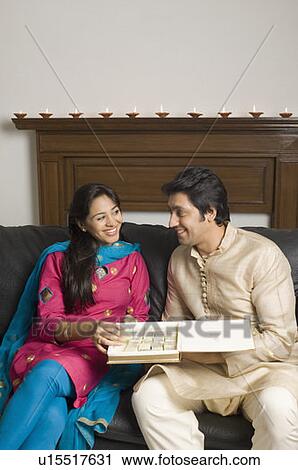 Stock Image - Close-up of a couple holding a box of sweets and smiling. Fotosearch