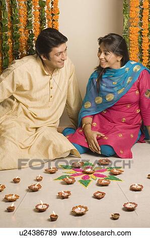 Stock Photo - Mid adult man and a young woman sitting in front of oil lamps. Fotosearch