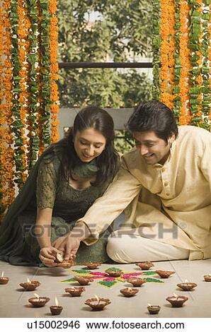 Mid adult man with a young woman lighting oil lamps View Large Photo Image Stock Photograph - Mid adult man with a young woman lighting oil lamps. Fotosearch