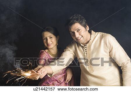 Stock Photo - Portrait of a couple holding a sparkler and smiling. Fotosearch