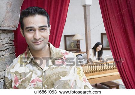 Portrait of a young man smiling with a young woman lying on the bed in the background View Large Photo Image Stock Image - Portrait of a young man smiling with a young woman lying on the bed in the background. Fotosearch