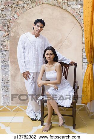 Portrait of a young woman sitting in an armchair with a young man standing behind her View Large Photo Image Stock Image - Portrait of a young woman sitting in an armchair with a young man standing behind her. Fotosearch