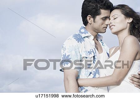 Side profile of a young couple romancing on the beach View Large Photo Image Stock Photo - Side profile of a young couple romancing on the beach. Fotosearch