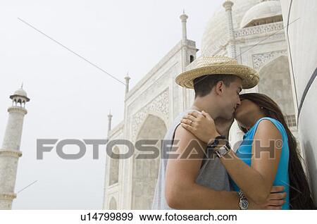 Stock Photo - Side profile of a young woman kissing a young man in front of a mausoleum, Taj Mahal, Agra, Uttar Pradesh, India. Fotosearch