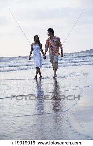 Young couple walking on the beach View Large Photo Image Stock Photograph - Young couple walking on the beach. Fotosearch