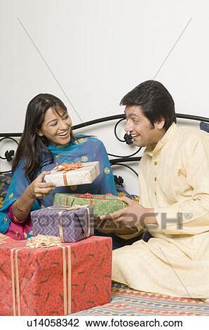 Young woman and a mid adult man holding diwali gifts and smiling View Large Photo Image Stock Image - Young woman and a mid adult man holding diwali gifts and smiling. Fotosearch