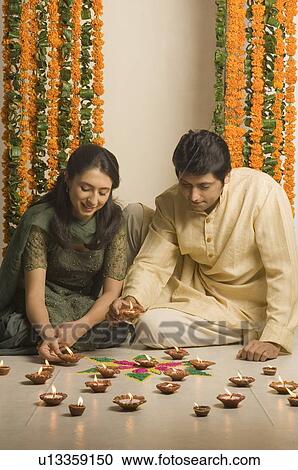 Young woman and a mid adult man arranging diwali lamps around a rangoli View Large Photo Image Stock Image - Young woman and a mid adult man arranging diwali lamps around a rangoli. Fotosearch