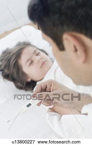 Close-up of a mid adult man checking temperature of his daughter View Large Photo Image Stock Photo - Close-up of a mid adult man checking temperature of his daughter. Fotosearch
