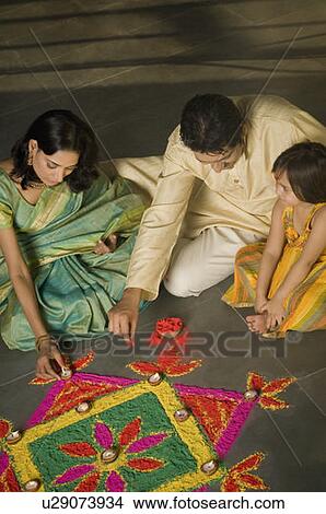 High angle view of a mid adult man and a young woman making rangoli with their daughter View Large Photo Image Picture - High angle view of a mid adult man and a young woman making rangoli with their daughter. Fotosearch