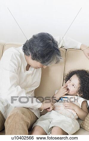 Mature woman sitting on a couch with her grandson View Large Photo Image Stock Photograph - Mature woman sitting on a couch with her grandson. Fotosearch