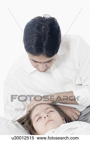 Mid adult man sitting beside his daughter sleeping on the bed View Large Photo Image Stock Photography - Mid adult man sitting beside his daughter sleeping on the bed. Fotosearch