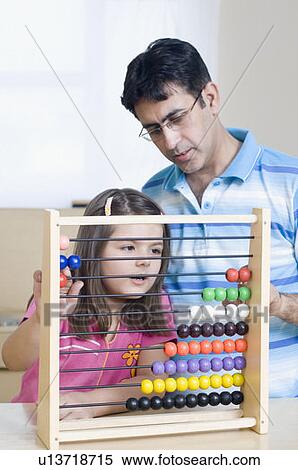 Stock Photography - Mid adult man teaching his daughter with an abacus. Fotosearch