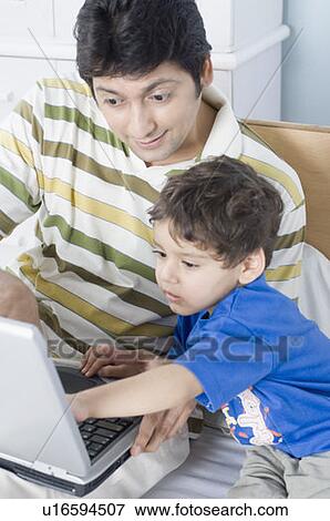 Mid adult man teaching his son with a laptop View Large Photo Image Stock Photo - Mid adult man teaching his son with a laptop. Fotosearch